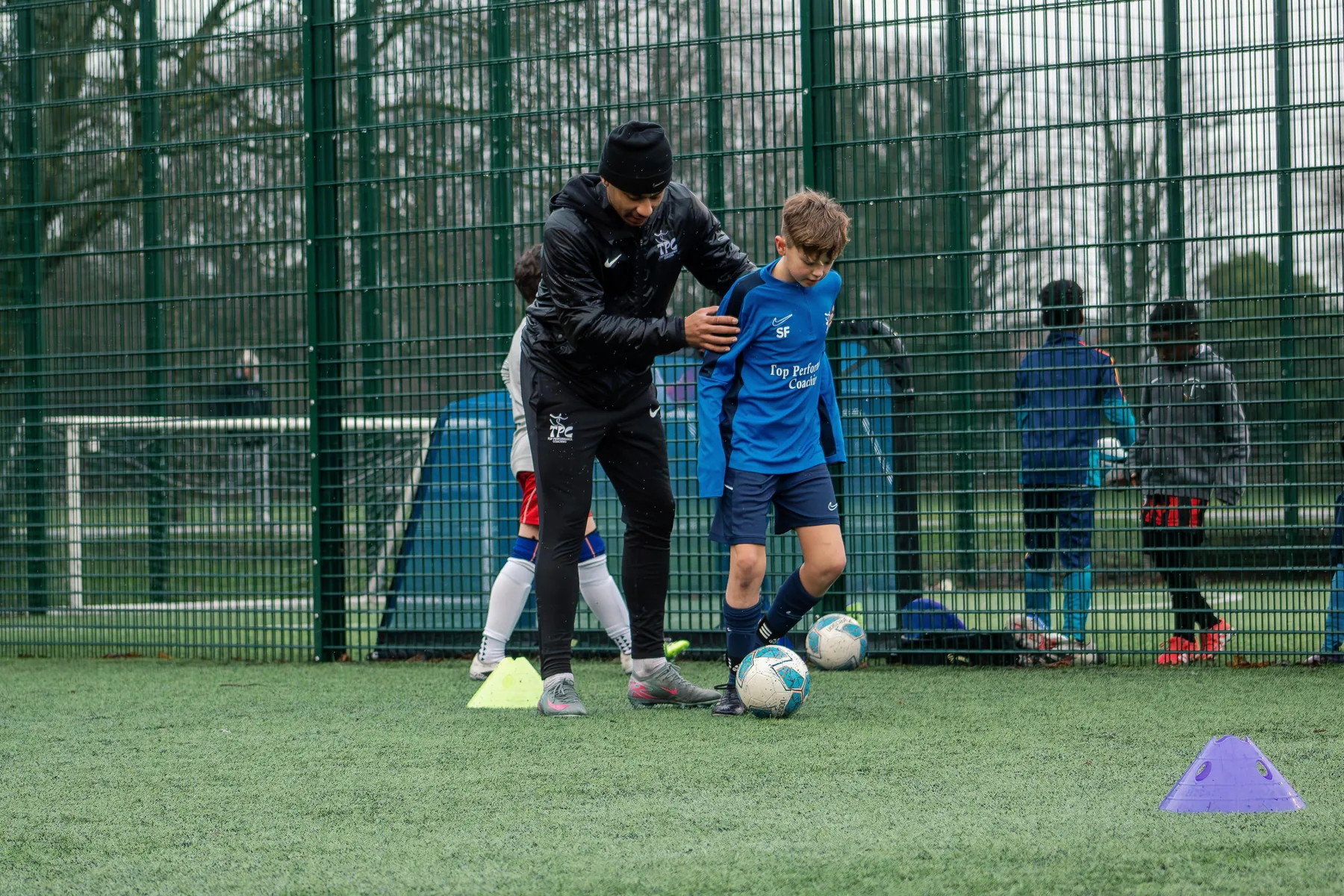 Tyreace coaching a player closely on the pitch
